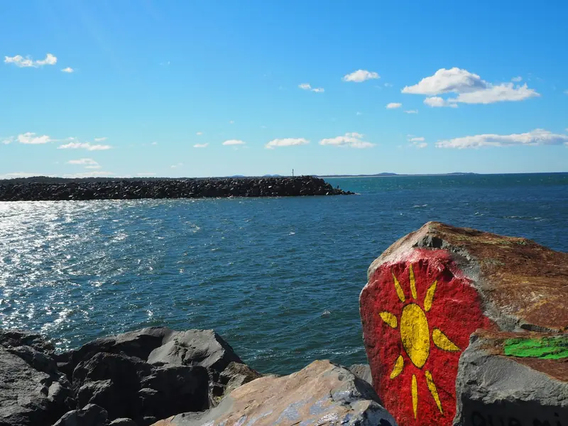A painted rock on the Port Macquarie breakwall, with the river mouth behind it