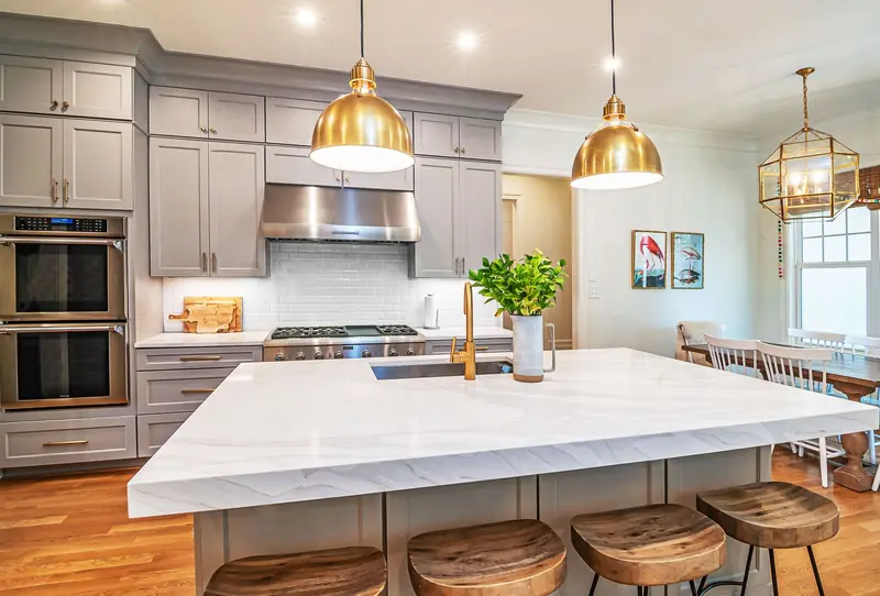 Renovated kitchen with a stone island and brass pendant lights