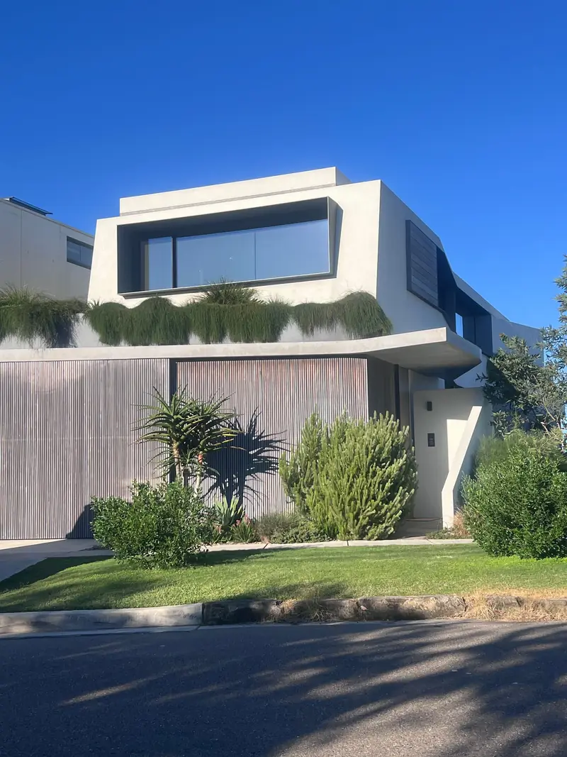 Contemporary rendered home with timber screening and a native garden