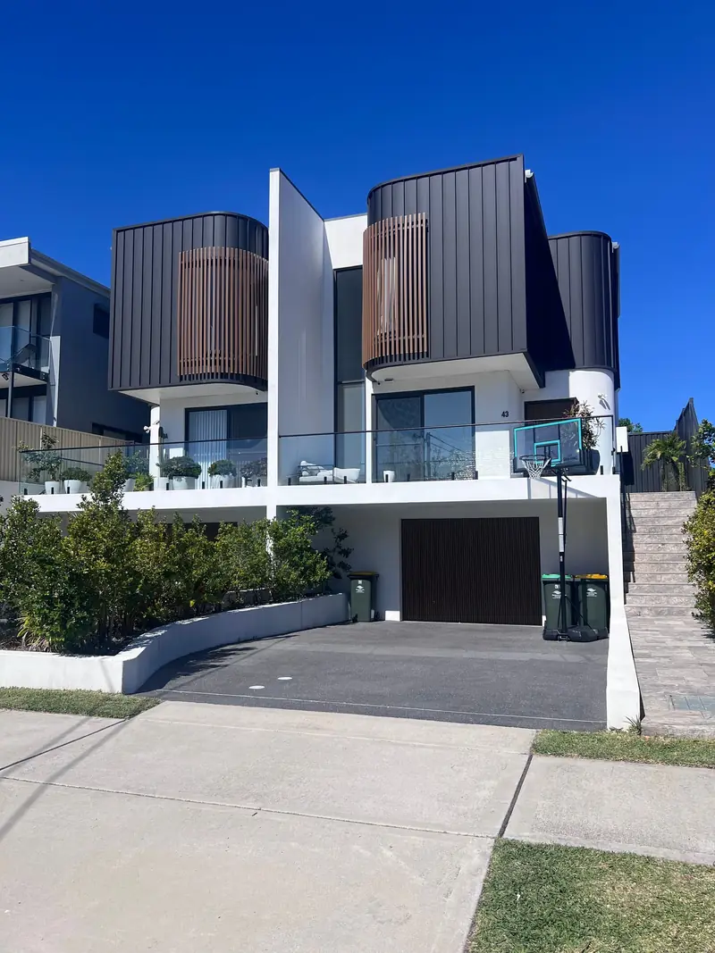 Modern two-storey home with dark cladding and a glass balcony