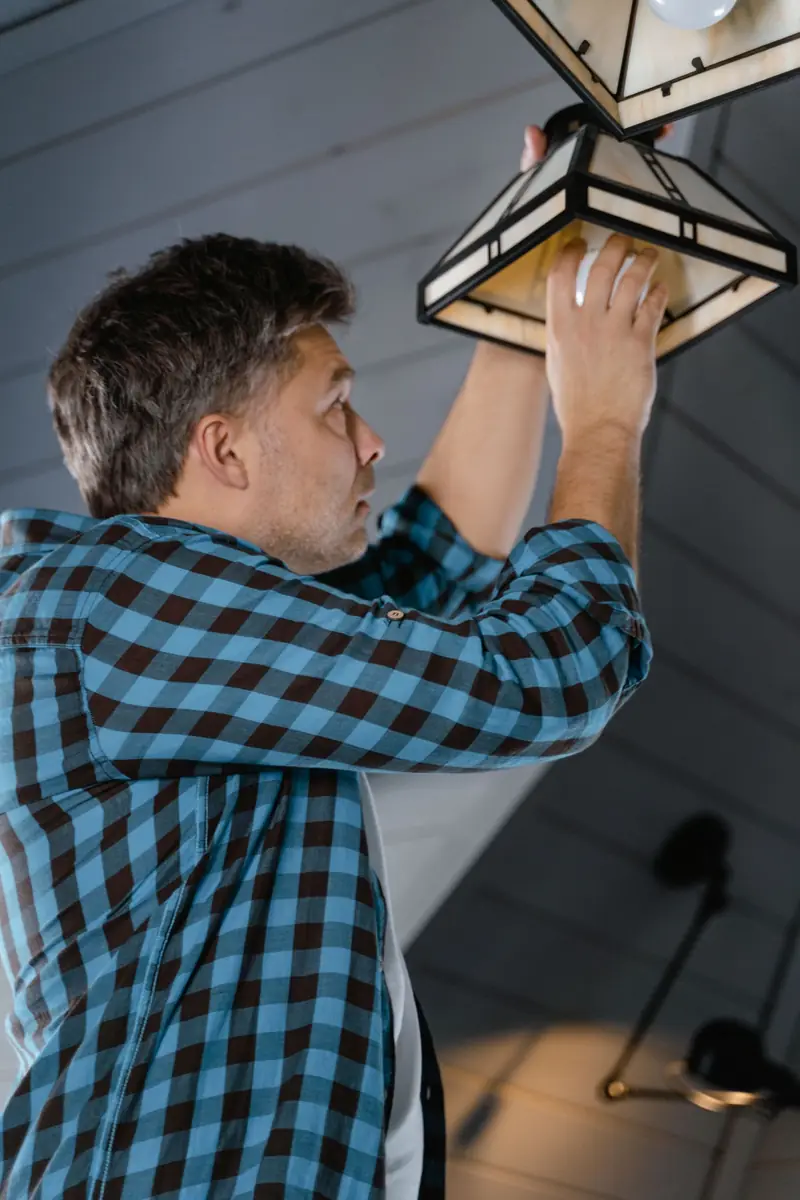 Electrician installing a pendant light in a living room